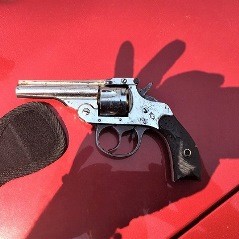 Close up of handgun on good of red car